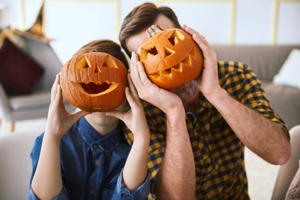 Father and boy with scary Halloween pumpkin Father and boy with scary Halloween pumpkin carving craft activity stock pictures, royalty-free photos & images