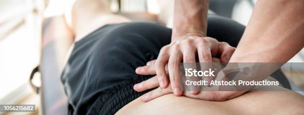 Therapist Giving Lower Back Sports Massage To Athlete Male Patient Stock Photo - Download Image Now