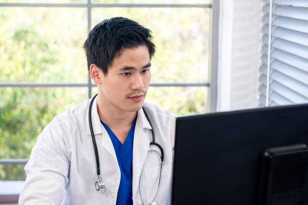 istock Young handsome Asian male doctor working in front of computer 1056215694