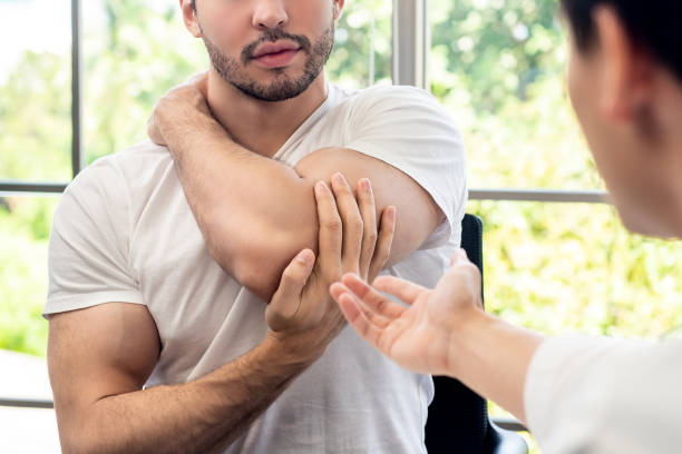 paziente sportivo che si consulta con il medico sul dolore muscolo in clinica - shoulder pain physical injury human arm foto e immagini stock