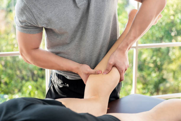 terapeuta masculino dando masaje de piernas y pantorrillas a paciente atleta en clínica - massaging men swedish culture male fotografías e imágenes de stock