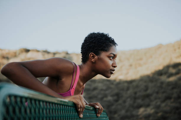 femme qui s’étend contre un banc de parc - brassière de sport photos et images de collection