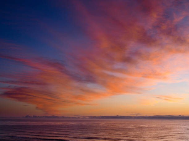 istock Pink orange light clouds over ocean at dawn 1056218072