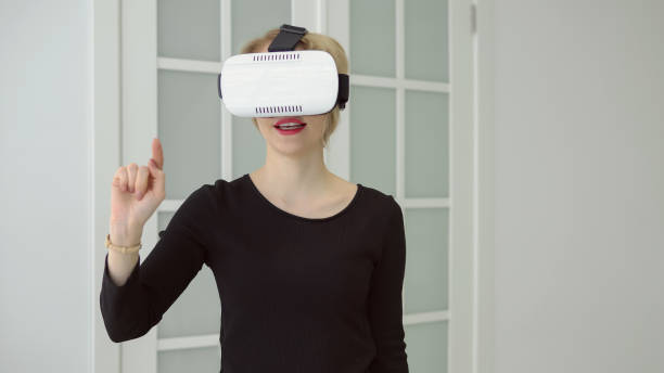 istock Young woman getting experience using VR headset glasses of virtual reality at home much gesticulating hands 1056222894