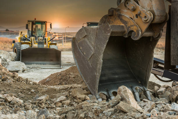 grande escavatore che lavora alla costruzione di una strada - earth mover working field dirt foto e immagini stock