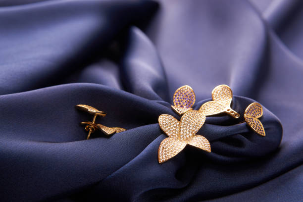 Beautiful gold ring and earrings with precious gemstone stones on blue silk background with copy space. Beautiful precious women's jewelry, close-up