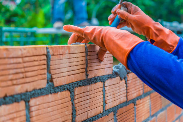 istock Hand of construction worker putting down mortar paste on top of unfinished brick wall preparing for the next layer of bricks 1056239742