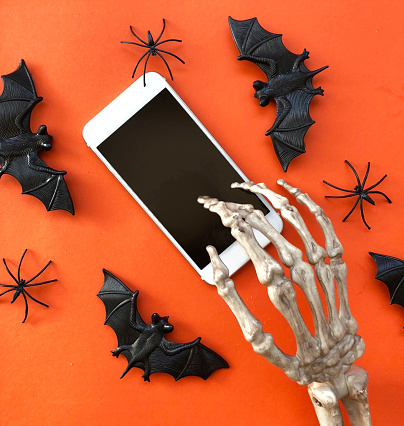 SKeleton using phone. Spiders and bats background