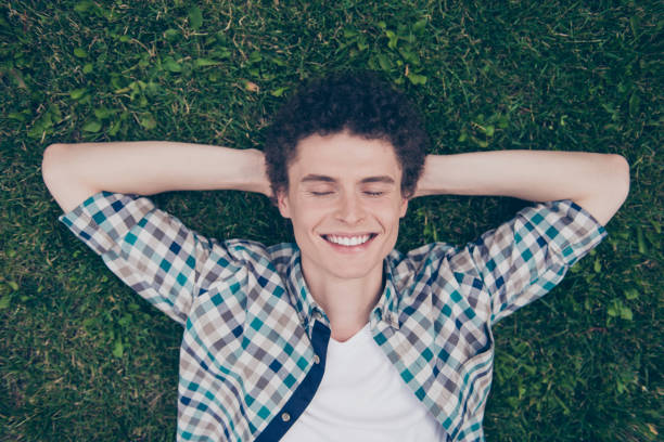 istock Curly haired cute attractive smiling handsome guy wearing casual shirt sleeping lying on green grass outside, enjoying, work pause, weekend 1056249032