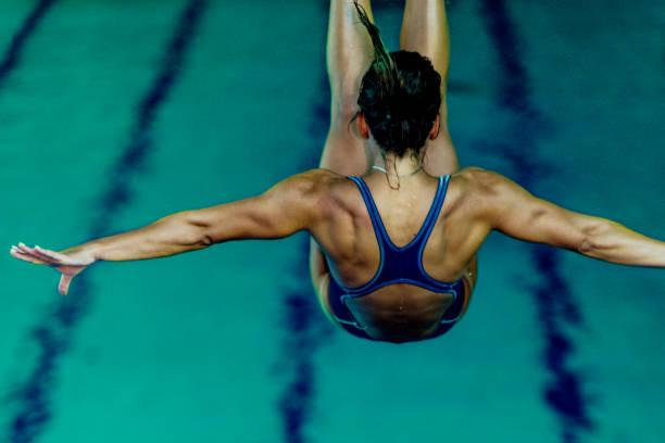 Female diver jumping into the pool Female diver jumping into the pool from diving board jump board stock pictures, royalty-free photos & images