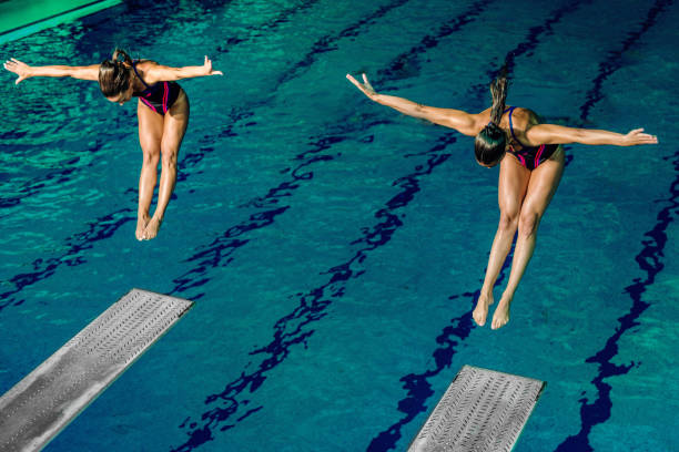 Female divers Two female divers diving into the pool. Tandem diving diving into water photos stock pictures, royalty-free photos & images
