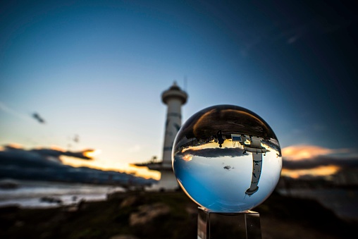 The lighthouse is reflected in the glass ball