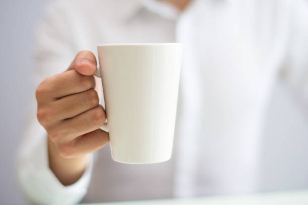 istock Close-up of office employee drinking coffee from mug 1056270246