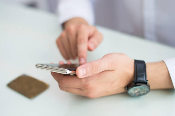 istock Close-up of unrecognizable man with wristwatch using smartphone 1056270314