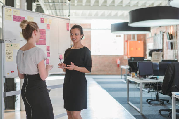 istock Young businesswomen discussing over whiteboard 1056272196