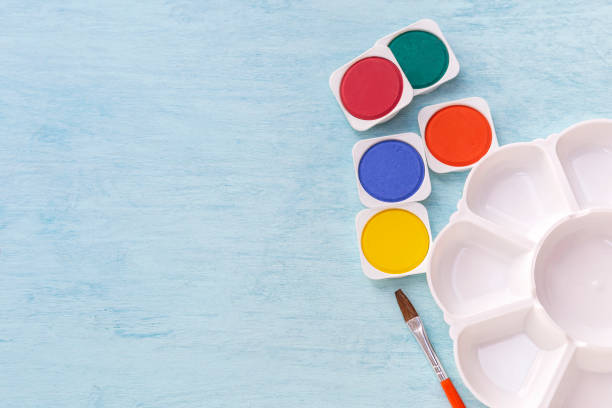 istock Colorful watercolor tablet and paint palette with space on blue table background 1056284886