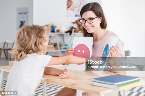 Smiling Counselor Holding Pictures During Meeting With Young Patient With Autism Stock Photo - Download Image Now