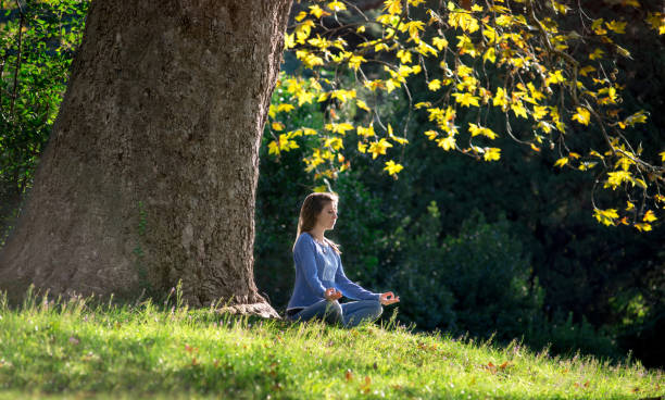 istock Girl meditates sitting on the grass under a maple tree in autumn 1056291676