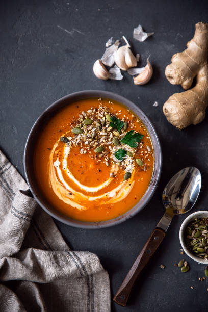 Orange creme soup with pumpkin and seeds. Serving with ginger, parsley and garlic. Dinner table with winter squash soup. View from the top. pumpkin soup photos stock pictures, royalty-free photos & images