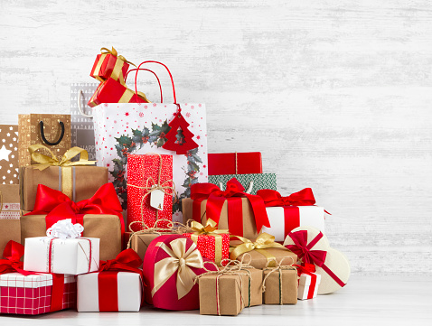 Lots of Christmas gift boxes in front of a white rustic wooden wall with copy space