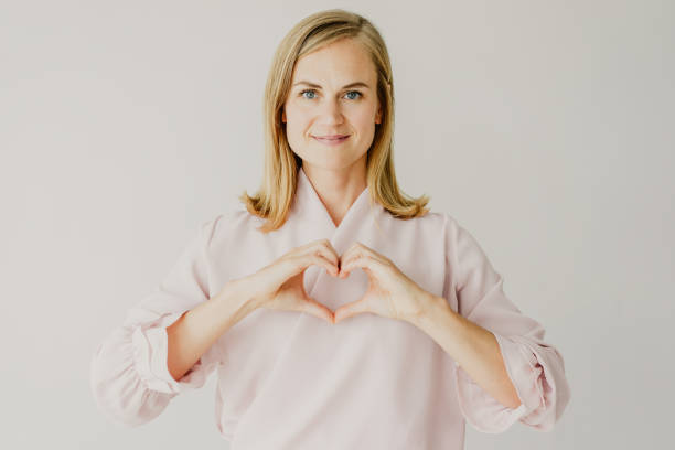 istock Smiling peace-loving lady showing heart 1056292796