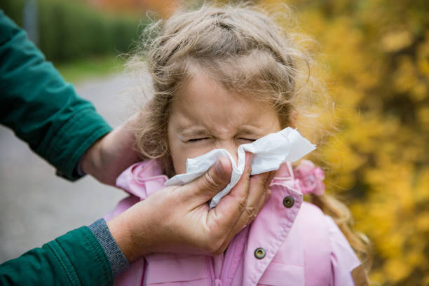 Father wiping daughter's nose with handkerchief Father wiping daughter's nose with handkerchief. Sick little girl with cold and flu standing outdoors. Preschooler sneezing, coughing, having runny red nose. Autumn street background blowing nose photos stock pictures, royalty-free photos & images