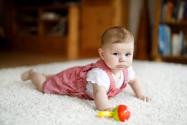 カラフルなラトル教育おもちゃで遊ぶかわいい赤ちゃん。リトル少女、カメラ目線とクロール - portrait germany party bed ストックフォトと画像