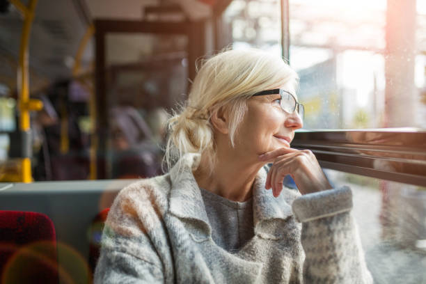 Senior woman in the bus Senior Woman Looking Through Window While Traveling In Bus public transportation stock pictures, royalty-free photos & images