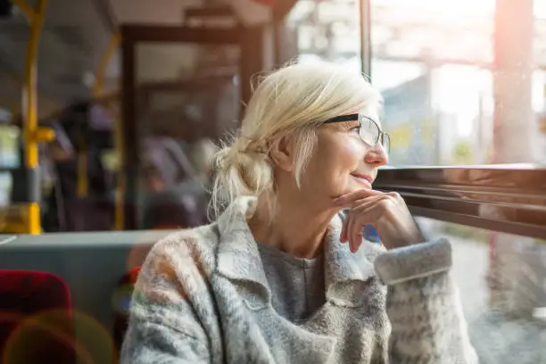 Senior Woman Looking Through Window While Traveling In Bus