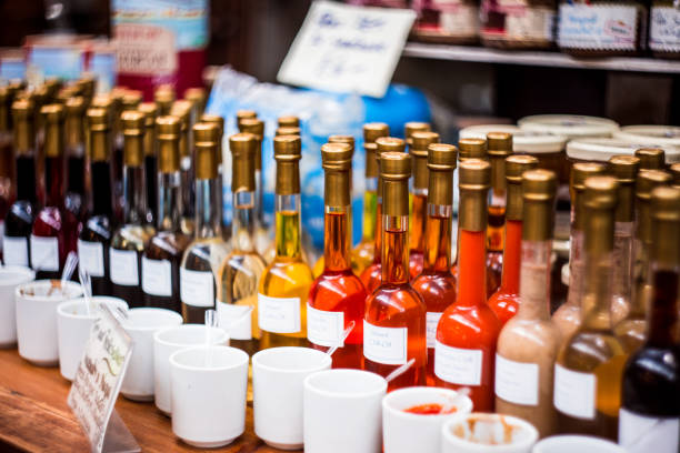 Close up color image depicting a large variety of different sauces - including hot chilli sauce - in a row and in glass bottles for sale at a food market in London, UK. The table has a reflective glass surface. Each of the sauces has its own price tag. Room for copy space.