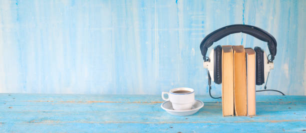 audio book concept, with books, headphones and cup of coffee, panorama, grunge blue background, good copy space
