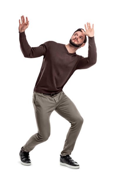 istock A bearded man in casual garb stands cowering under something dangerous above him. 1056306666