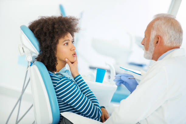 Dentist appointment. Closeup of a mid 50's male dentist examining an early 30's African american patient. She's having some pains in her lower teeth and jay. jaw pain stock pictures, royalty-free photos & images