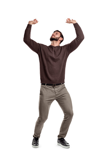 Un hombre con barba en ropa casual intenta sostener algo pesado desde arriba en un fondo blanco. photo