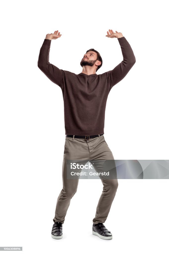 Un hombre con barba en ropa casual intenta sostener algo pesado desde arriba en un fondo blanco. - Foto de stock de Hombres libre de derechos