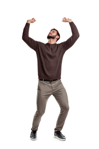 un hombre con barba en ropa casual intenta sostener algo pesado desde arriba en un fondo blanco. - arms raised fotografías e imágenes de stock