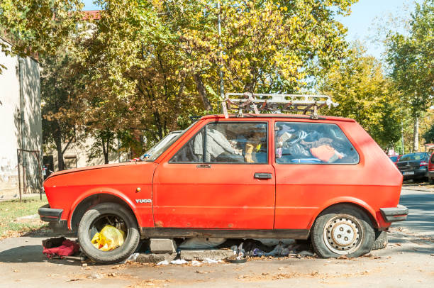 old rusty red broken and damaged yugo car full of junk parked and abandoned on the street. - car obsolete old editorial imagens e fotografias de stock