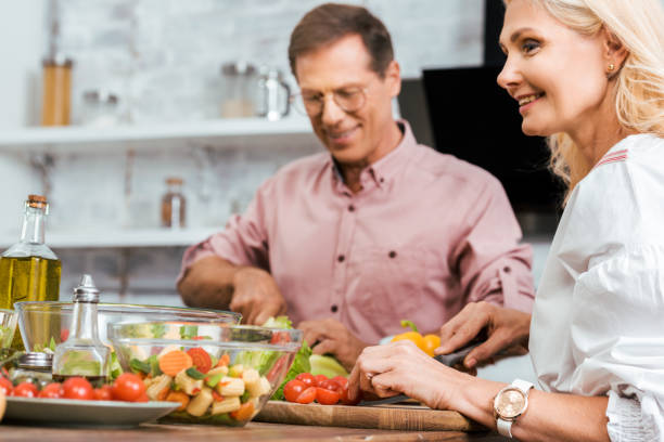 istock smiling wife and husband preparing salad for dinner together in kitchen 1056313112