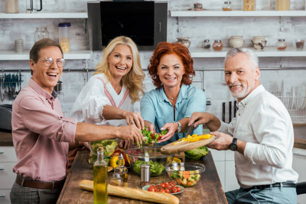 istock happy old friends preparing salad for dinner together at home 1056313184