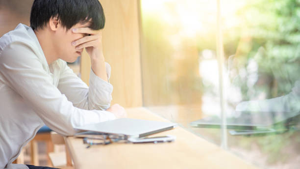 istock Overworked Asian businessman feeling stressed while working with laptop computer in cafe. Business problem or burnout syndrome concepts 1056320434
