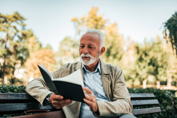 чтение книги в парке. - men reading outdoors book стоковые фото и изображения