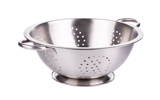 Steel strainer sieve metal bowl. It is isolated in a white background. Close-up.