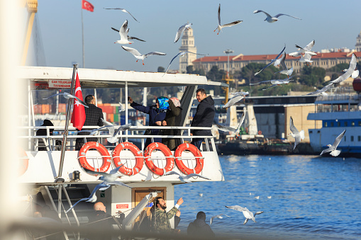 Istanbul, Turkey- February 09, 2018: People on a ferry throwing bread crumbs to seagulls.