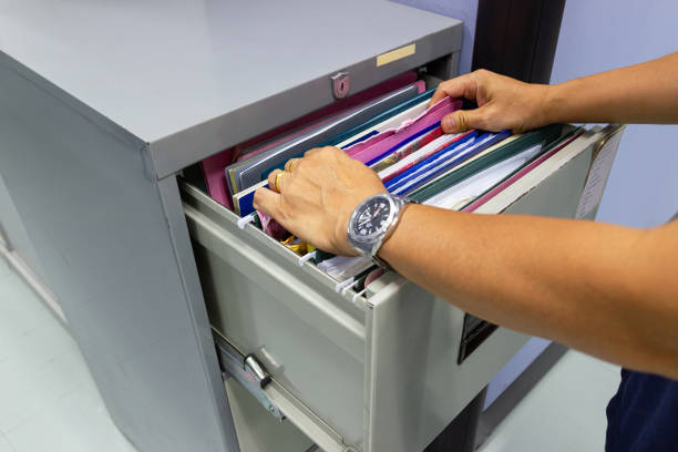istock Hand of Man Search files document in a file cabinet in work office 1056337114