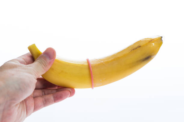 trzymanie banana na rękach z prezerwatywą wyizolowanym na białym tle - single object sensuality education isolated zdjęcia i obrazy z banku zdjęć