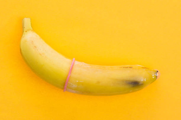 banan z prezerwatywą wyizolowany na żółtym tle - single object sensuality education isolated zdjęcia i obrazy z banku zdjęć