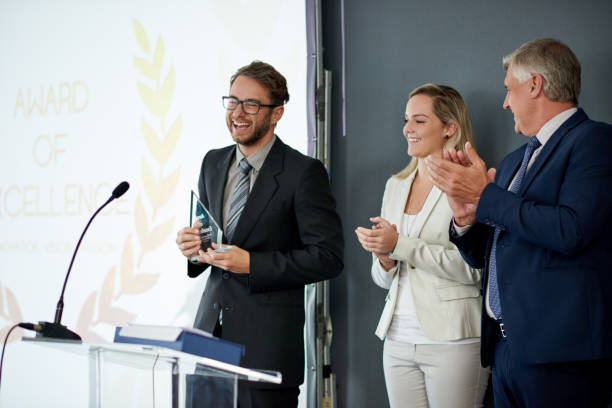 Thank you for honoring me today Shot of a young businessman being awarded a prize during an awards giving ceremony at a conference awards ceremony stock pictures, royalty-free photos & images