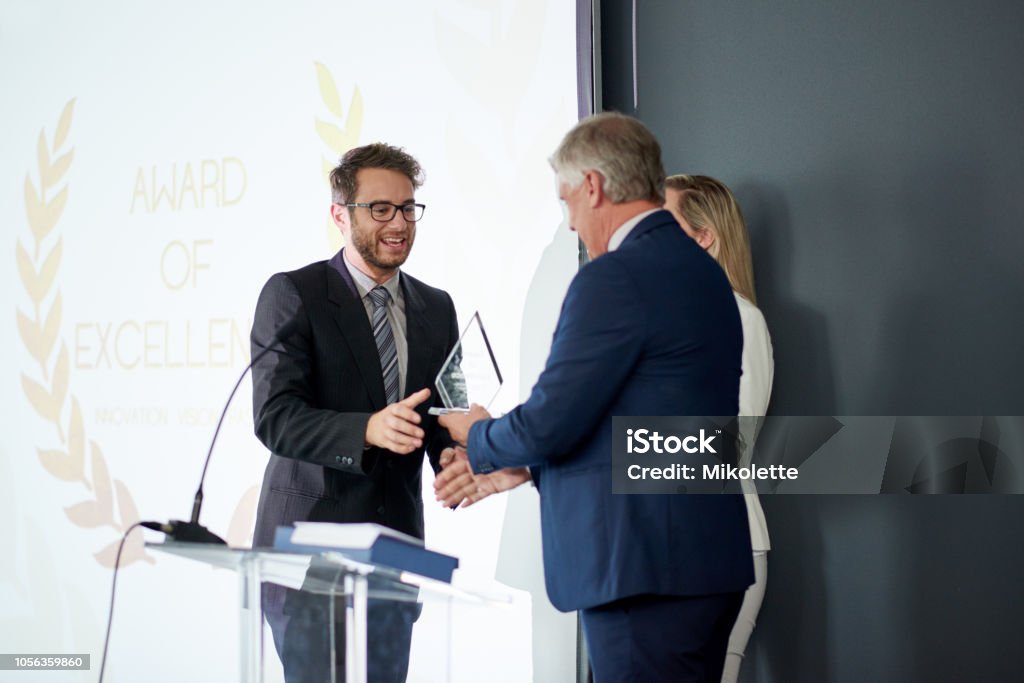 Workplace recognition makes all the difference Shot of a young businessman being awarded a prize during an awards giving ceremony at a conference Award Stock Photo