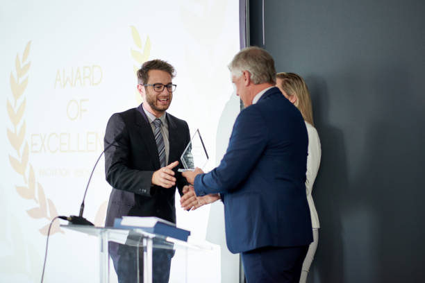 Workplace recognition makes all the difference Shot of a young businessman being awarded a prize during an awards giving ceremony at a conference awards ceremony stock pictures, royalty-free photos & images