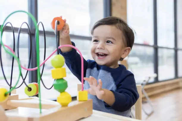 Photo of Toddler boy enjoys playing with toys in waiting room
